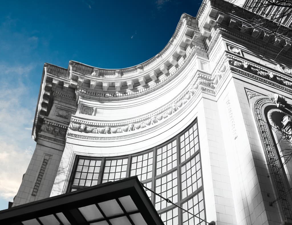 The curved white terra-cotta facade of the Coliseum Building at Pike Street and 5th Avenue in downtown Seattle, photographed against a clear sky.