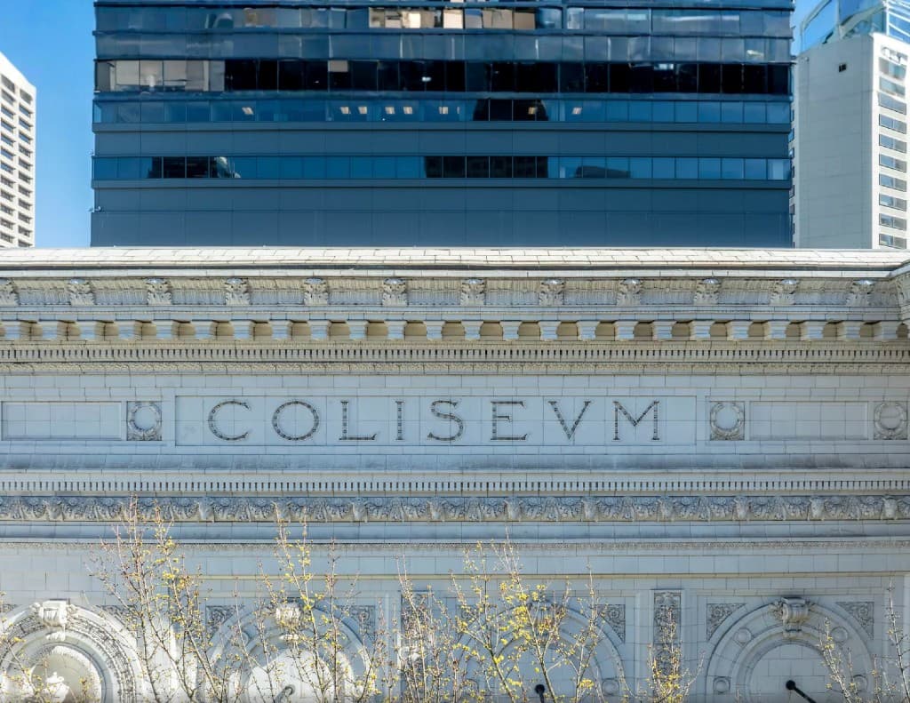 The stone facade inscription reading COLISEUM across the upper exterior band of the historic building
