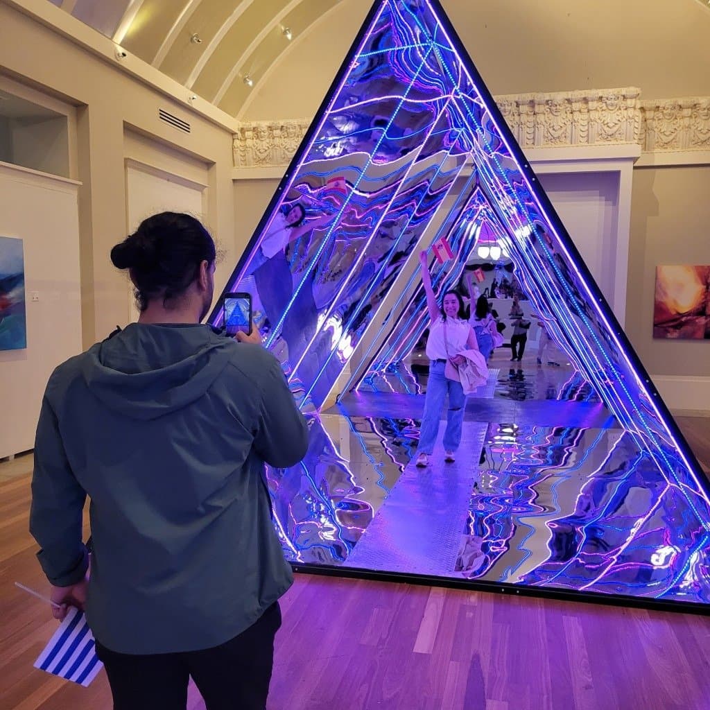 A visitor photographs the mirrored light pyramid inside the Coliseum of Art at Pike and 5th.
