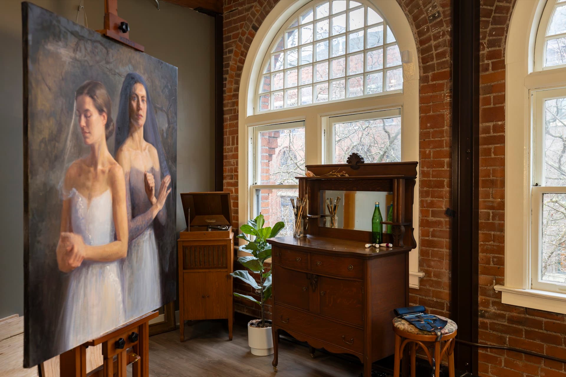 Finished and unfinished paintings in a Seattle Prize studio under an arched window