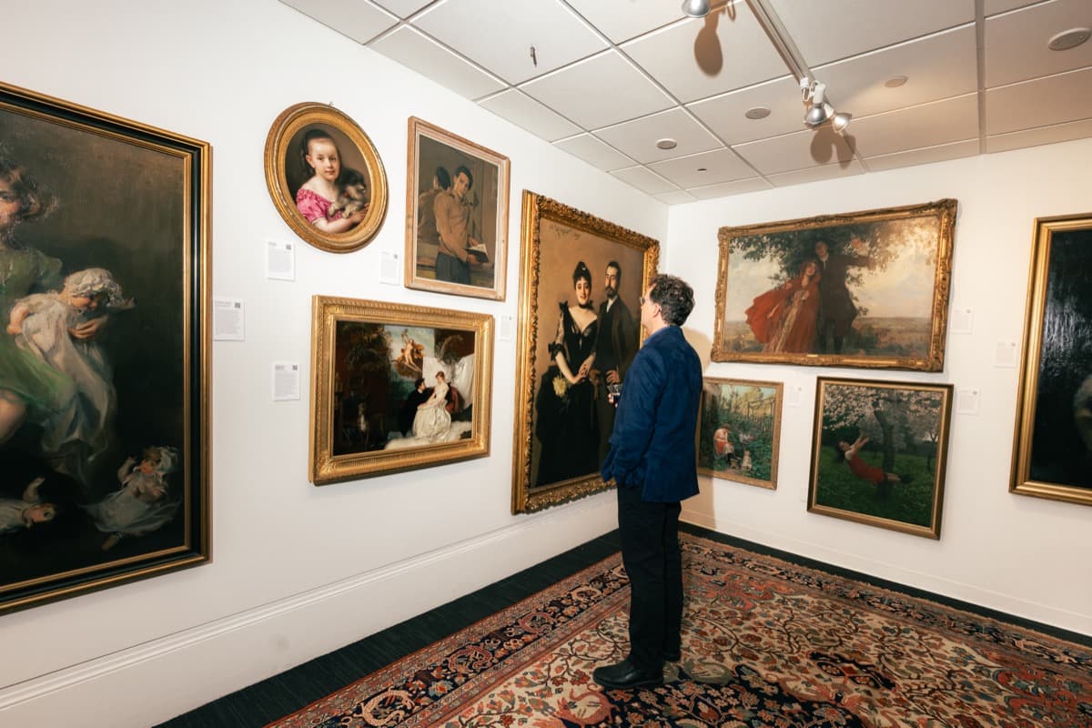 A quiet gallery room hung salon-style with classical paintings
