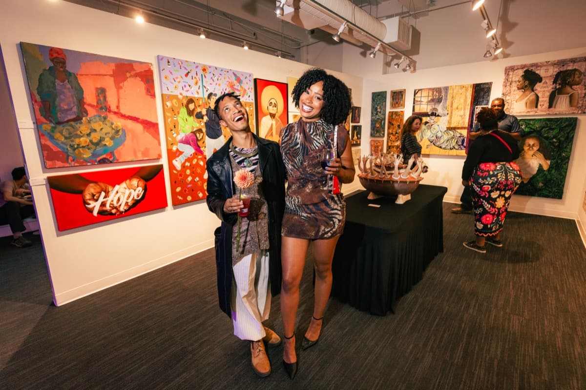 Guests laughing among bold contemporary paintings at a salon evening